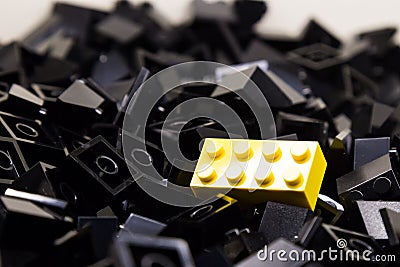 Pile of black color building blocks with selective focus and highlight on one particular yellow block using available light Stock Photo