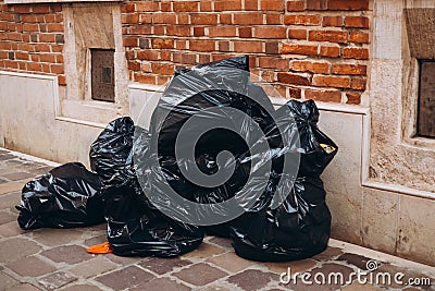 Pile of black garbage on the footpath at side road in big city, pollution trash. Many garbage plastic bags black waste Stock Photo