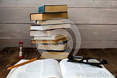Pile of books and hourglass glasses and pencil Stock Photo