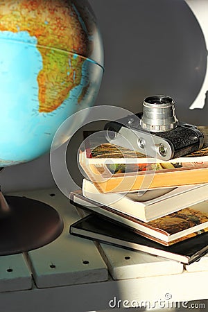 Pile of books, old film photo camera and a globe on white wooden table. Concept of travel, planning a dream trip Stock Photo