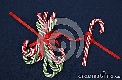 Pile Caramel sugar canes tied with a red ribbon on a blue background. Christmas background. Concept of Christmas and New Year. Stock Photo