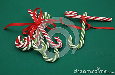 Pile Caramel sugar canes tied with a red ribbon on a green background. Christmas background. Concept of Christmas and New Year. Stock Photo