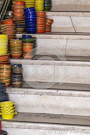 Pile of ceramic bowls of various sizes and colors on stairs Stock Photo