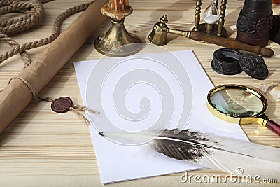 A pile of clean paper, a retro inkwell with black ink, a goose feather, magnifying glass, a scroll with a seal, an old hourglass a Stock Photo