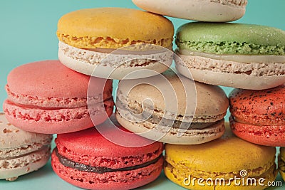 Pile of colorful macaroons stacked up like a tower in turquose pastel background (Selective focus) - Closeup Stock Photo