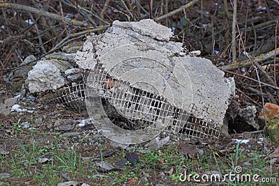 A pile of construction debris from pieces of gray concrete in green grass Stock Photo