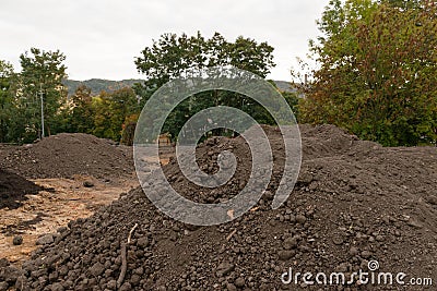 Pile of dark construction gardening soil mud land earth dirt heap pile mound, freshly dug, with some wet soil and leaves Stock Photo