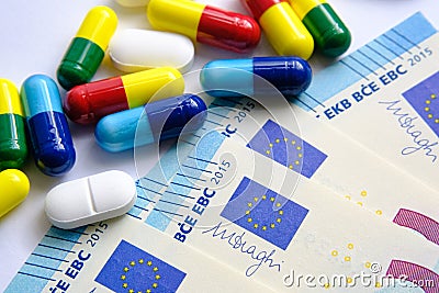 Pile of of different colouful pills placed next to 20 euro banknotes. Illustrative for cost of medical bills, health insurance and Stock Photo