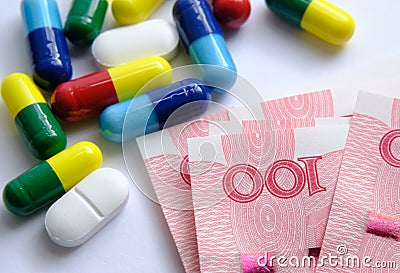 Pile of different colouful pills placed next to 100 yuan banknotes. Illustrative for cost of medical bills, health insurance and o Stock Photo