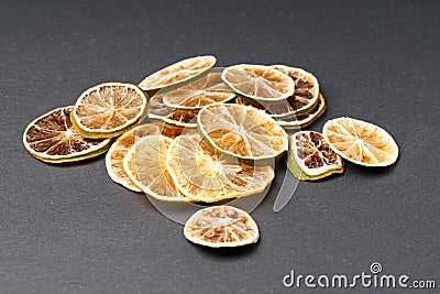 A pile of dried citrus slices. Lemon and lime. Against a dark background. Stock Photo