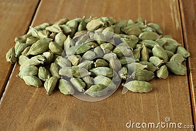 Pile of dry scattered unrefined cardamom seeds lying on wooden boards Stock Photo