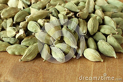 Pile of dry scattered unrefined cardamom seeds lying on wooden boards Stock Photo