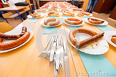 Pile of flatware in front of grilled and fresh handmade sausages on white plate arranged for sausage tournament Stock Photo