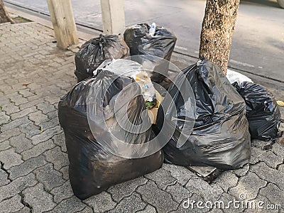 Pile garbage black bag plastic on roadside.Trash bag on the footpath. Stock Photo