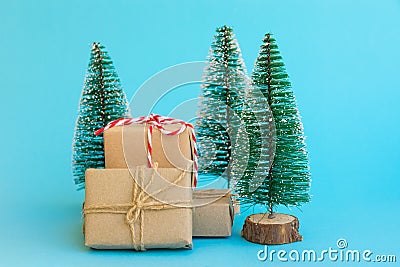 Pile of gift boxes wrapped in craft paper tied with twine red white ribbon Christmas trees on mint blue background. New Year Stock Photo