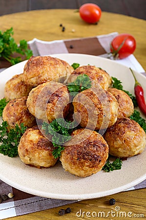 A pile of golden meat balls on a plate with parsley on a wooden table. Stock Photo