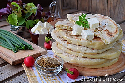 Pile of homemade flat bread with lettuce, cheese, onion and radish on a wooden background. Mexican flatbread taco. Indian Naan. Stock Photo