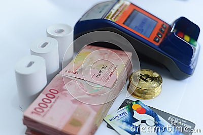Pile of hundred thousand rupiah banknotes along with BANK BRI credit cards and bitcoins and also an EDC ELECTRONIC DATA CAPTURE Editorial Stock Photo