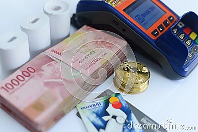 Pile of hundred thousand rupiah banknotes along with BANK BRI credit cards and bitcoins and also an EDC ELECTRONIC DATA CAPTURE Editorial Stock Photo