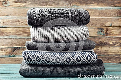 Pile of knitted winter clothes on wooden background, sweaters, knitwear Stock Photo