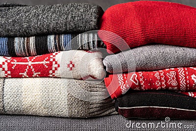 Pile of knitted woolen sweaters autumn colors on wooden table. Clothes with different knitting patterns folded in stack. Warm cozy Stock Photo