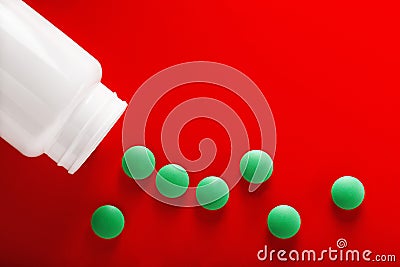 Pile of medical pills in green and white jar on clean red background. Layout for the designer. Stock Photo