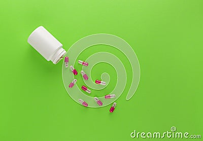 A pile of medical pills in a white jar on a clean green background. Layout for the designer Stock Photo
