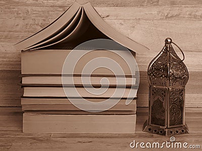 A pile of old home shaped books and a silver Ramadan (Ramazan) lantern. Sepia colour. Stock Photo