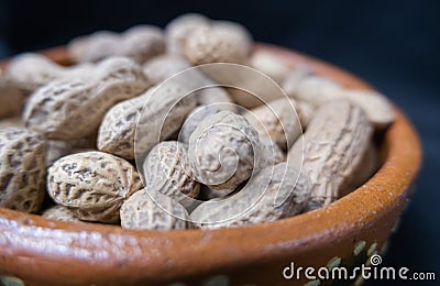 Pile of peanuts in a brown clay bowl Stock Photo