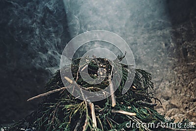 a pile of pine branch smoking on the holy sacred fire with a ray of sun peaking in from the top Stock Photo