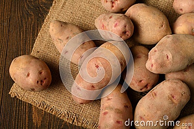 A pile of potatoes on burlap on a dark wood background Stock Photo