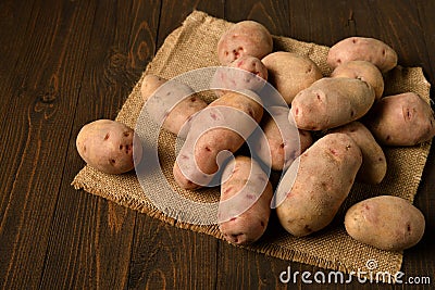 A pile of potatoes on burlap on a dark wood background Stock Photo