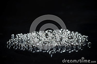 A pile of pure silver granules. Isolated on mirror black background. Stock Photo