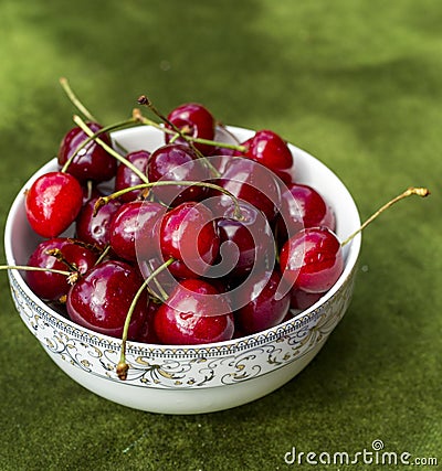 Pile of red cherries in ceramic bowl on green grass Stock Photo