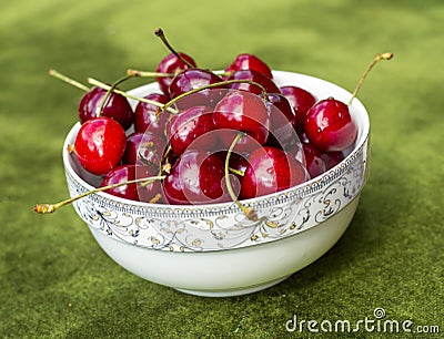 Pile of red cherries in ceramic bowl on green grass Stock Photo