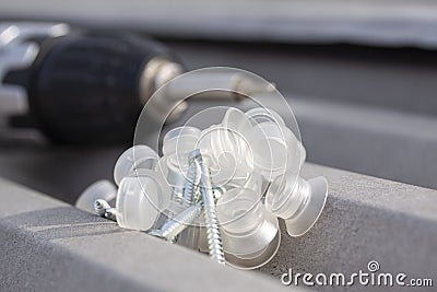 Pile of roofing screws with clear caps for rapezoidal metal roof mounting and a power drill Stock Photo