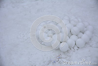A pile of round snowballs for a game of children molded from snow against a background of loose snow. March 2018 Ukraine. Stock Photo