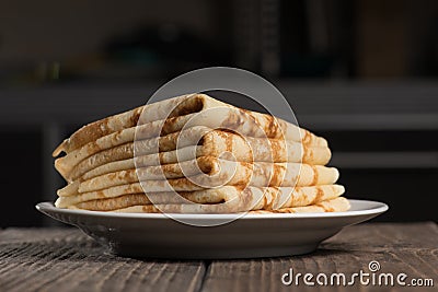 Pile of russian pancakes in plate against dark background Stock Photo