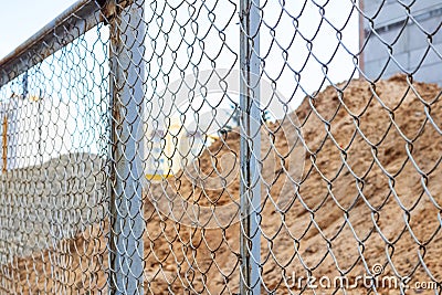 Pile of sand at construction site behind metal fense Stock Photo