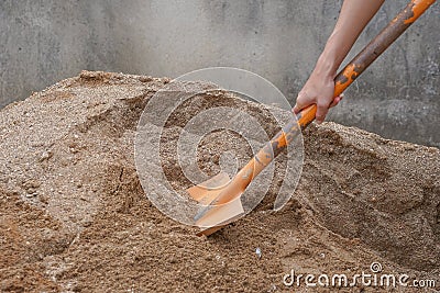 Pile of sand, hand of a construction worker scooping sand for mix mortar on construction site Stock Photo