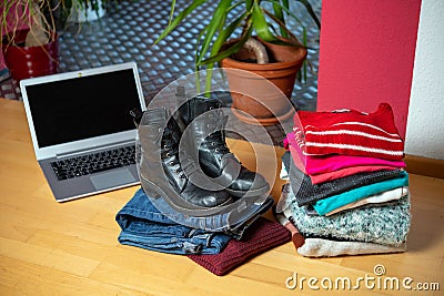 Pile of second hand clothing and shoes with computer on floor Stock Photo