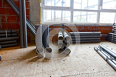 Pile of sewerage tubes placed on the floor in the unfinished residential edifice Stock Photo