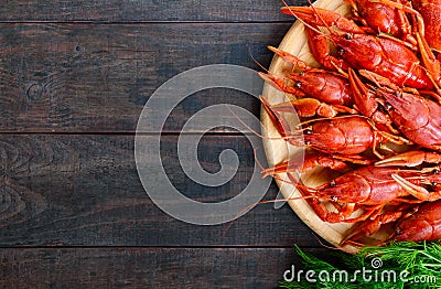 A pile of tasty boiled crawfish on a round wooden tray on a dark table. Top view. Stock Photo