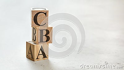 Pile with three wooden cubes - letters CBA meaning Cost Benefit Assessment on them, space for more text / images at right side Stock Photo