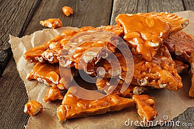 Pile of traditional peanut brittle candy pieces, close up on an old wood background Stock Photo