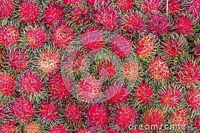 Pile of tropical rambutan fruits. Pink and spiky rambutan are piled on a table at a farmers market. Stock Photo