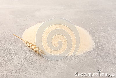 Pile of uncooked organic semolina and spikelet on grey table Stock Photo