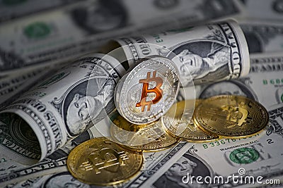 Pile of US dollar cash. Next to it are a number of gold bitcoins and a silver digital cryptocurrency coin. Stock Photo