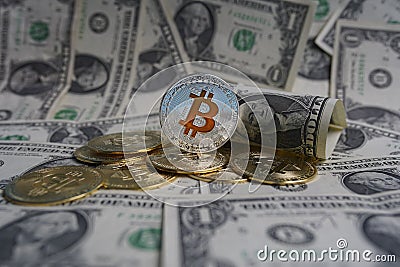 Pile of US dollar cash. Next to it are a number of gold bitcoins and a silver digital cryptocurrency coin. Stock Photo