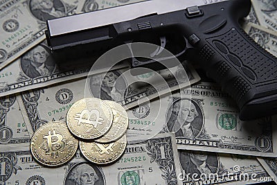 Pile of US dollars cash and a black pistol. Next to it are several gold bitcoin coins. Stock Photo